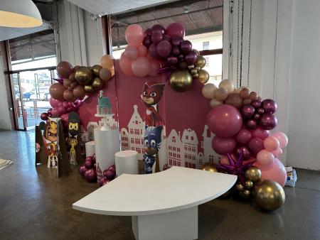 we love creating this one for six-year-old‘s birthday. we used three of our panel, backdrops painted pink with our white vinyl cityscape done in house, and then also our cylinder rentals that we wrapped with the cityscape as well to match this awesome theme our customer had. Balloon Specialties Santa Rosa (415)858-4427